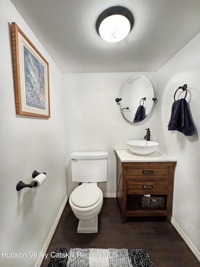 bathroom featuring wood-type flooring, toilet, and vanity