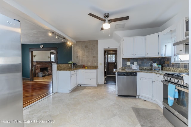 kitchen featuring white cabinets, decorative backsplash, stainless steel appliances, and dark stone counters