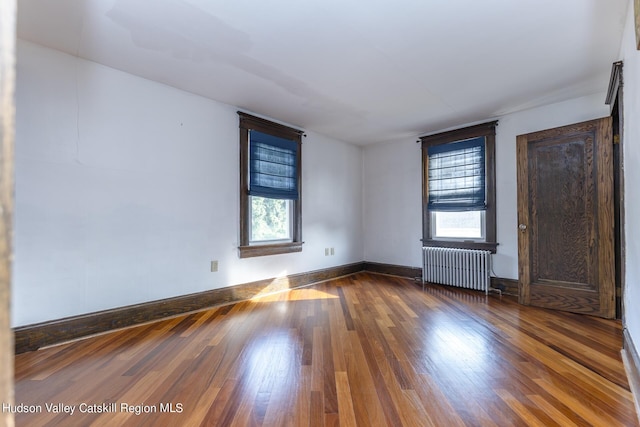 unfurnished room featuring hardwood / wood-style flooring, plenty of natural light, and radiator