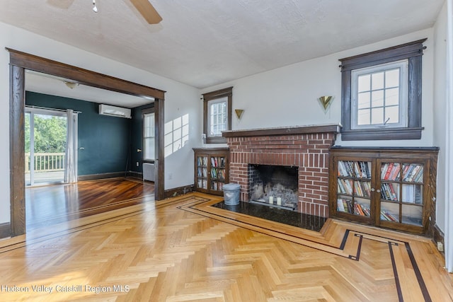 living room with a wall mounted air conditioner, parquet flooring, a textured ceiling, and a brick fireplace