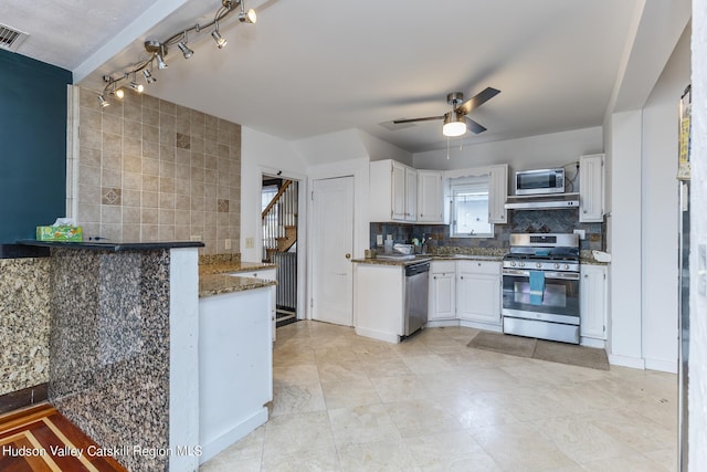 kitchen with stainless steel appliances, tasteful backsplash, dark stone countertops, kitchen peninsula, and white cabinets