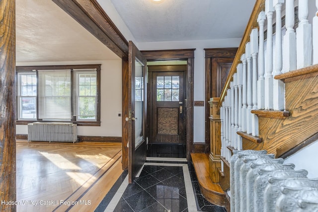 entrance foyer with dark parquet flooring, a textured ceiling, plenty of natural light, and radiator