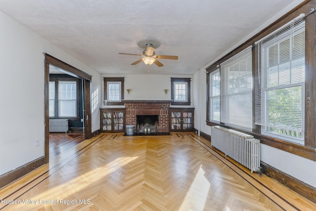 unfurnished living room with radiator heating unit, parquet flooring, and a wealth of natural light