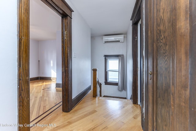 hall with a wall unit AC and light wood-type flooring