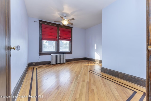 unfurnished room featuring hardwood / wood-style flooring, ceiling fan, and radiator