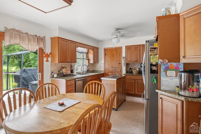 kitchen featuring appliances with stainless steel finishes, a ceiling fan, a sink, backsplash, and a center island