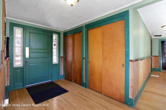 entrance foyer with light hardwood / wood-style floors, ornamental molding, and a wealth of natural light