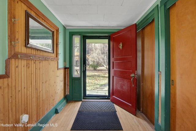 doorway featuring light wood-type flooring and wooden walls