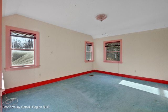 unfurnished room featuring dark colored carpet and lofted ceiling