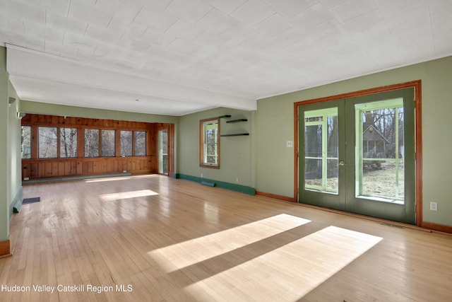 unfurnished living room with french doors, a baseboard heating unit, and light wood-type flooring