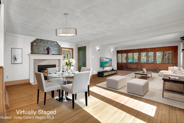 dining area with a tiled fireplace, crown molding, and hardwood / wood-style flooring