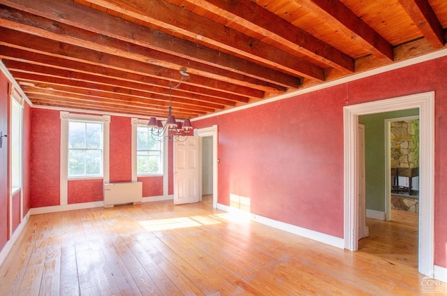 spare room with light wood-type flooring, a chandelier, baseboards, and beamed ceiling