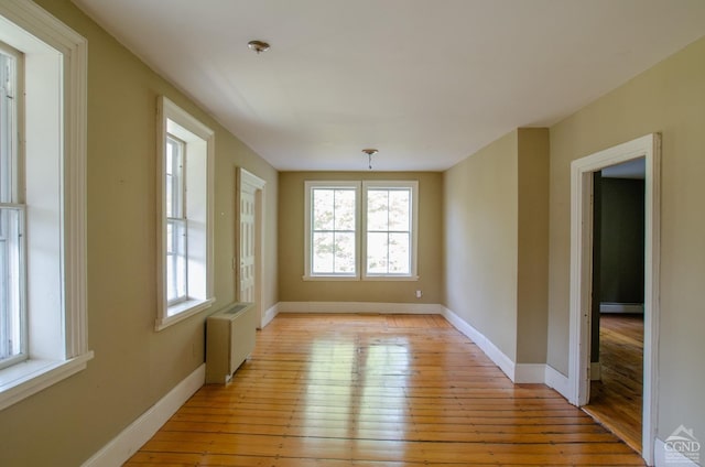 unfurnished dining area with plenty of natural light, light wood-type flooring, baseboards, and radiator heating unit