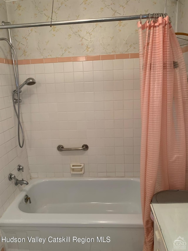bathroom featuring wallpapered walls, shower / bathtub combination with curtain, and vanity