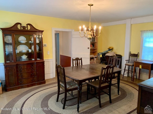 dining room with a chandelier, wainscoting, and light tile patterned floors