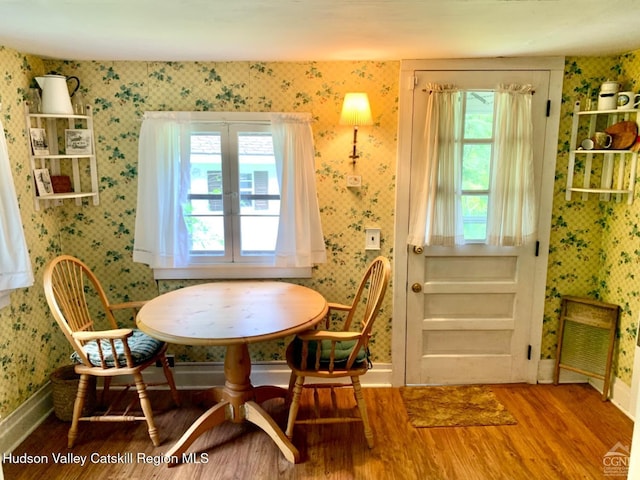 dining room featuring wallpapered walls, wood finished floors, and baseboards