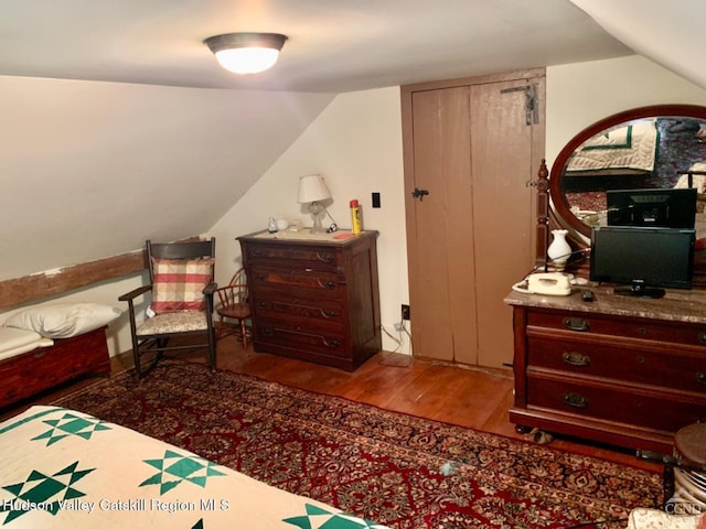 bedroom featuring wood finished floors and lofted ceiling