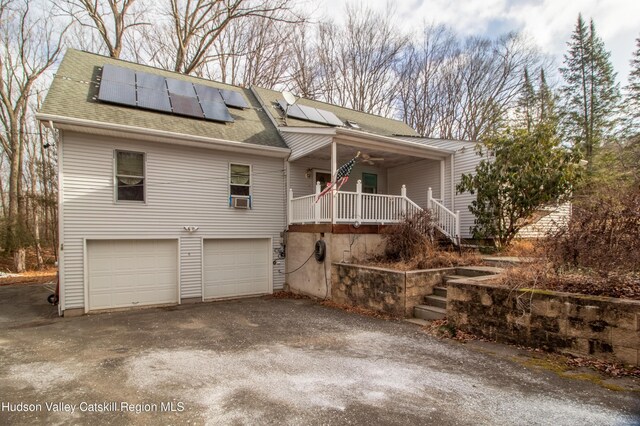 view of front of house with a garage, cooling unit, solar panels, and covered porch