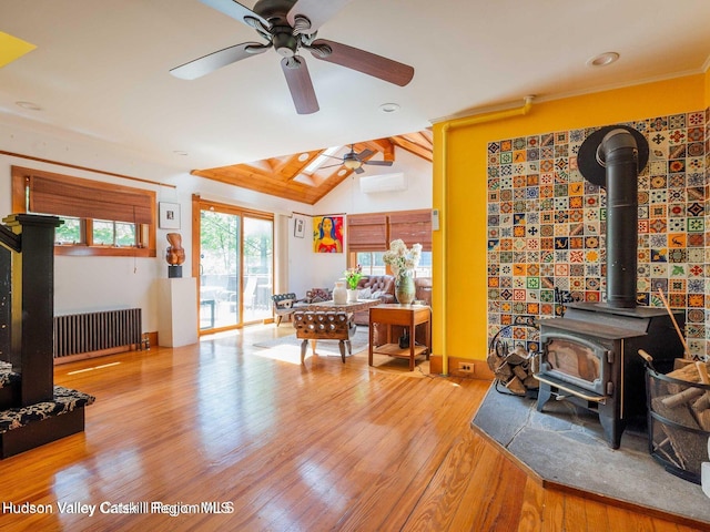 12 Library Ln, Woodstock, NY 12498 - living area featuring radiator heating unit, a wood stove, a ceiling fan, wood finished floors, and an AC wall unit