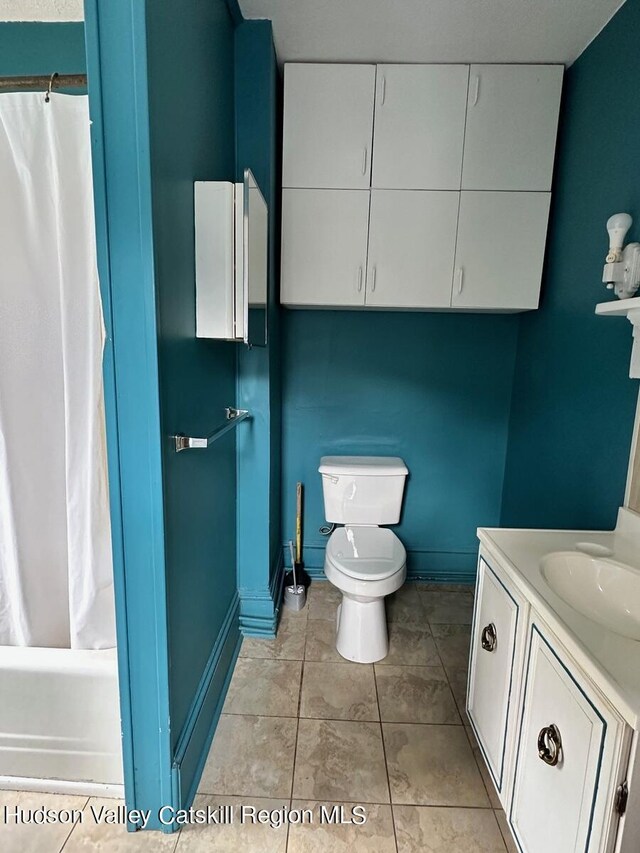 full bathroom featuring toilet, vanity, baseboards, tile patterned floors, and shower / tub combo with curtain