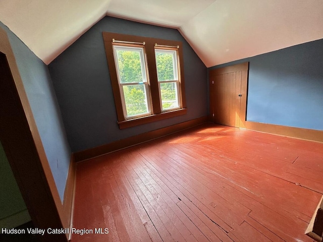 additional living space with light hardwood / wood-style floors and vaulted ceiling