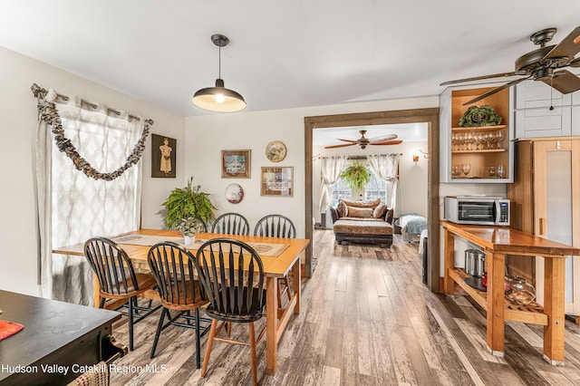 dining area with ceiling fan and wood-type flooring