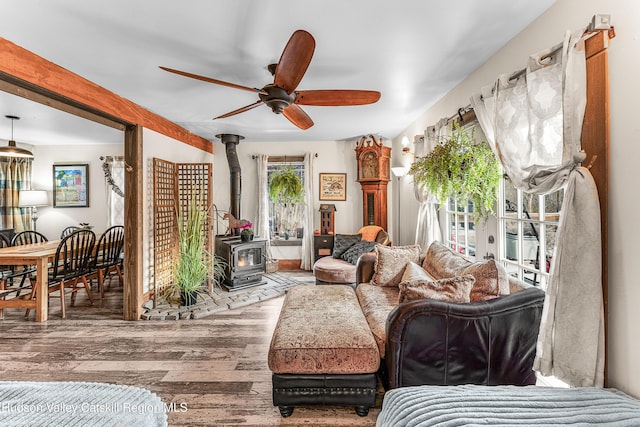 living room featuring a wood stove, ceiling fan, and wood-type flooring