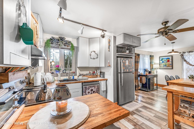 kitchen with stainless steel appliances, ceiling fan, sink, white cabinets, and light hardwood / wood-style floors