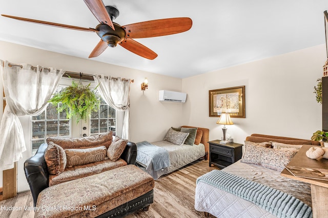 bedroom with a wall mounted air conditioner, ceiling fan, and light wood-type flooring