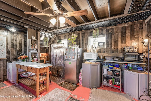 kitchen featuring sink, stainless steel refrigerator, ceiling fan, and wood walls