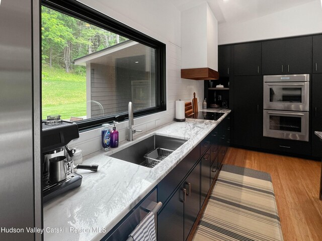 501 Birch St, Copake, NY 12516 - kitchen with double oven, light wood finished floors, dark cabinets, light stone counters, and backsplash