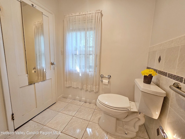 bathroom featuring tile patterned floors, toilet, and tile walls