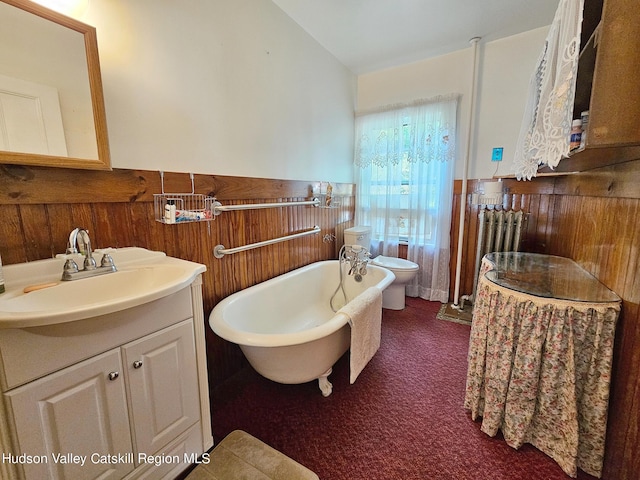 bathroom with a bath, vanity, toilet, and wooden walls