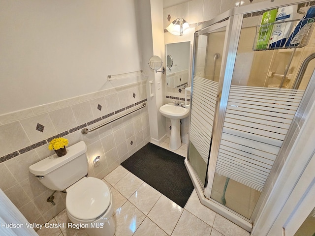 bathroom with sink, tile walls, tile patterned flooring, toilet, and a shower with shower door