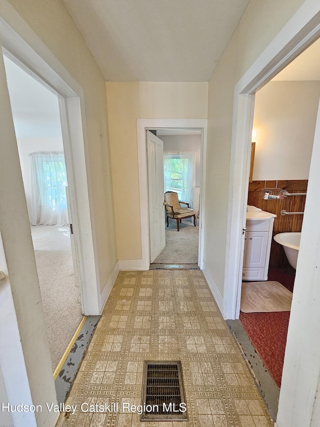 hallway with wood walls and light colored carpet