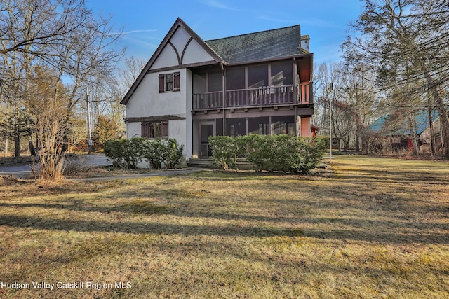 rear view of property featuring a yard and a sunroom