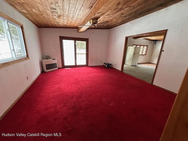 carpeted empty room featuring wooden ceiling, heating unit, and ceiling fan