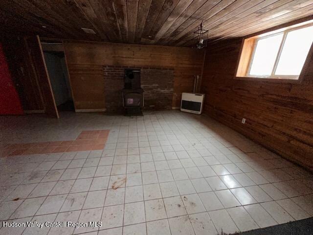 interior space with a wood stove, heating unit, wood walls, and wood ceiling