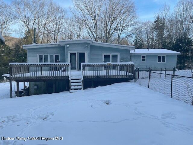 snow covered rear of property with a wooden deck