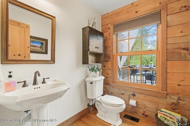 bathroom with wooden walls, sink, wood-type flooring, and toilet