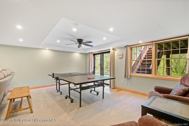 rec room featuring ceiling fan, a raised ceiling, and light carpet