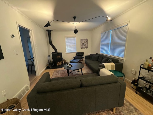 living room with ornamental molding, wood-type flooring, and a wood stove