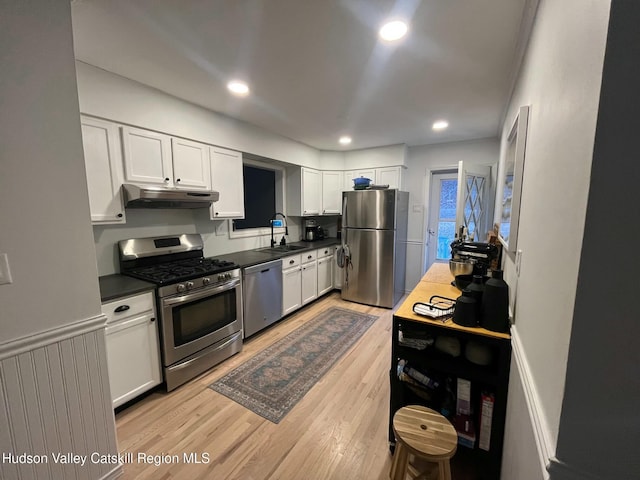 kitchen with appliances with stainless steel finishes, sink, light hardwood / wood-style flooring, and white cabinets