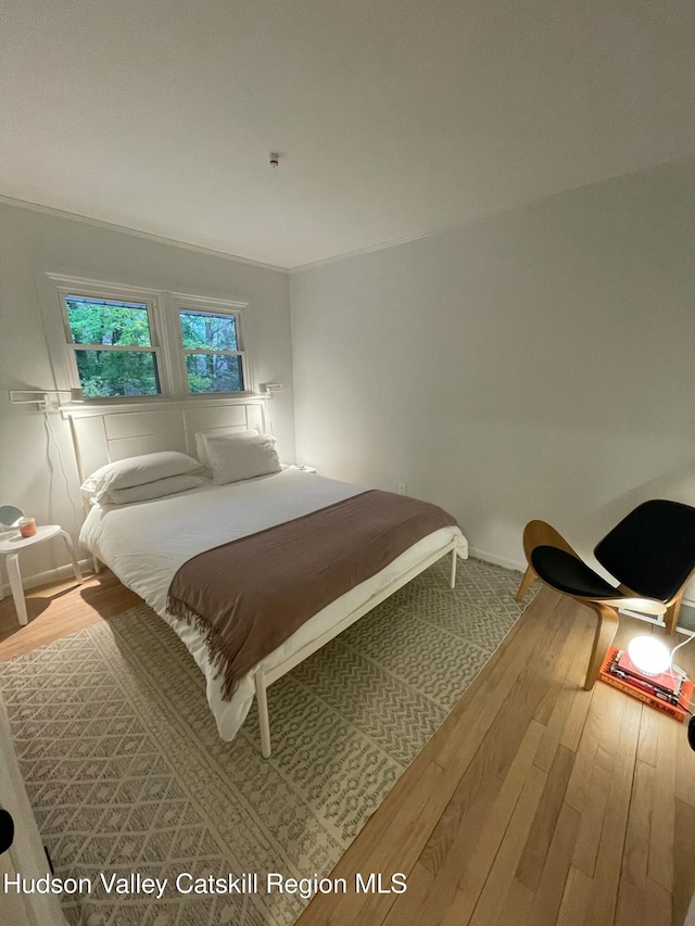 bedroom with hardwood / wood-style flooring and crown molding