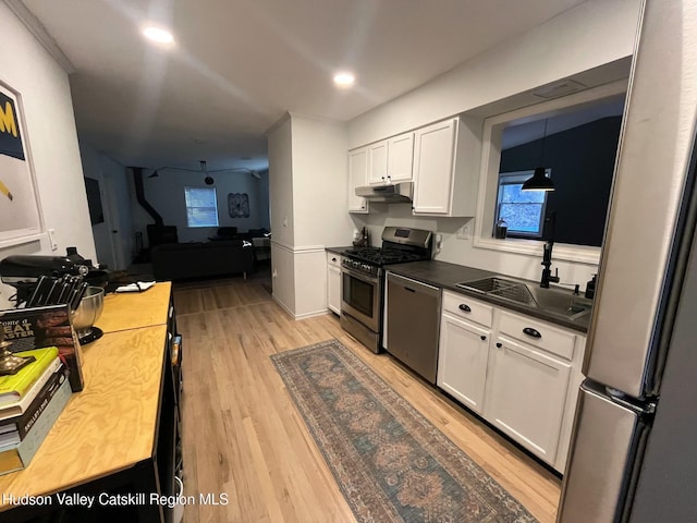 kitchen featuring pendant lighting, sink, light hardwood / wood-style flooring, appliances with stainless steel finishes, and white cabinets