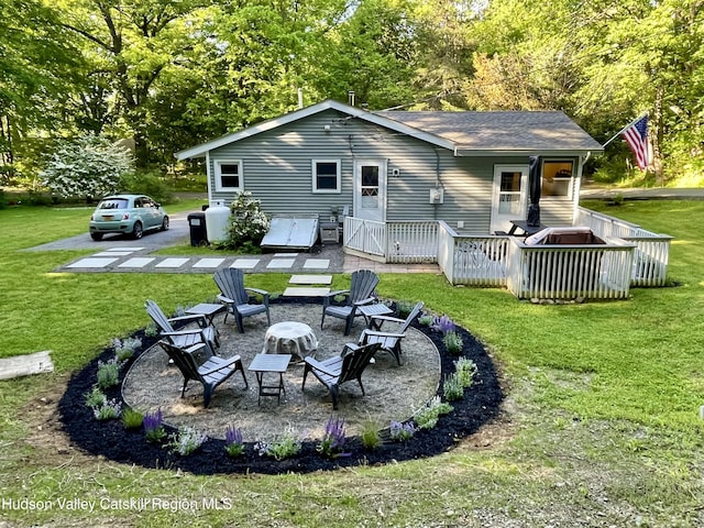 back of house featuring a wooden deck, a fire pit, a patio, and a lawn