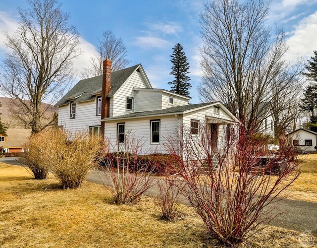 51 Division St, Hunter, NY 12442 - view of property exterior with a shingled roof, a chimney, and a lawn
