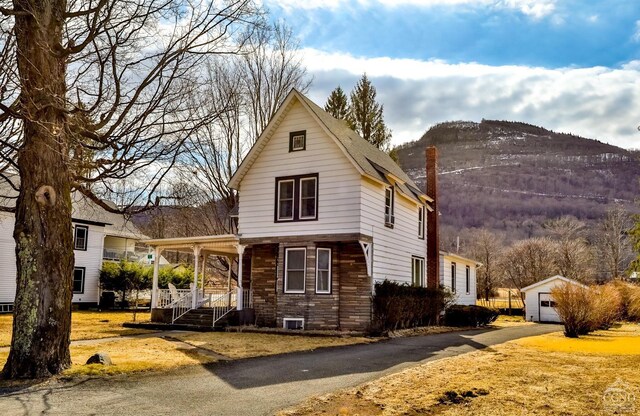51 Division St, Hunter, NY 12442 - view of front of house with covered porch, a mountain view, a detached garage, asphalt driveway, and an outdoor structure