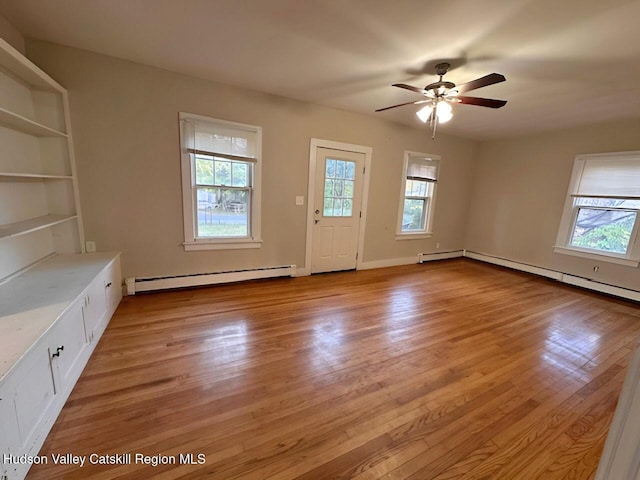 unfurnished living room featuring ceiling fan, a healthy amount of sunlight, light wood-type flooring, and baseboard heating