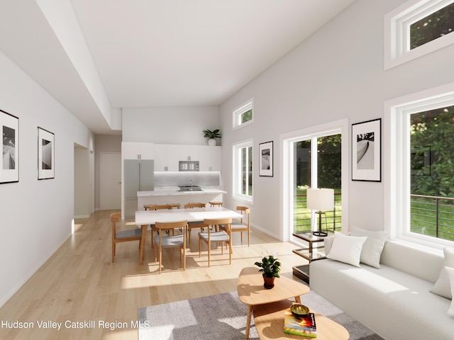 living room featuring plenty of natural light, light wood-type flooring, and high vaulted ceiling